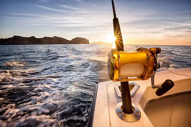 Big fishing reels on a boat in the ocean.  These reels are used to catch big game fish such as Mahi-mahi, dorado, tuna, sailfish, swordfish sharks and marlin.  They are used in tropical and cold water oceans.