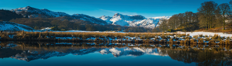 The crisp white snow capped peaks of Langdale reflecting in the tranquil blue surface of Elter Water near Ambleside in the idyllic landscape of the Lake District National Park, Cumbria, UK. ProPhoto RGB profile for maximum color fidelity and gamut.
