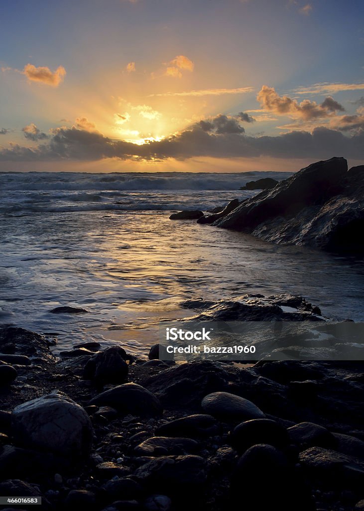 Coastal sunset. Sun setting at Dollar Cove, Gunwalloe on the Lizard Peninsula. Cornwall UK. Breaking Wave Stock Photo
