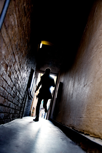 A mysterious running man silhouetted in a dark alleyway.