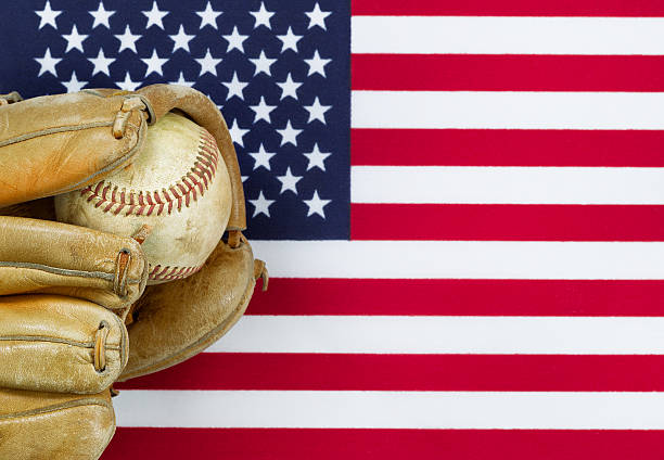 Close up image of worn leather mitt and used baseball with United States of America flag in background. Concept of baseball sport in America.