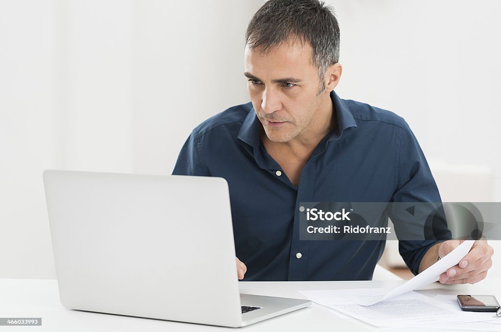 Mature Man Working At The Computer Portrait Of A Mature Man Looking At Laptop Holding Document Laptop Stock Photo