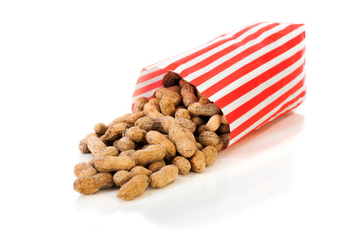 A tall pager bag of Roasted Salted Peanuts spilling onto a white background