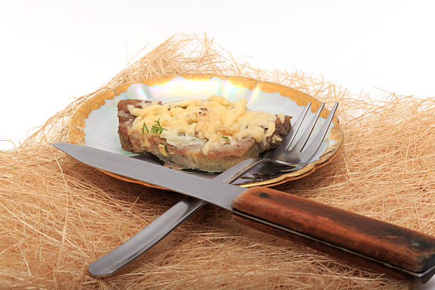 Delicious meat under cheese and onions on a plate.