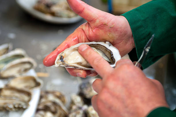 istock Using a finger to smooth out a freshly shucked oyster 466050624