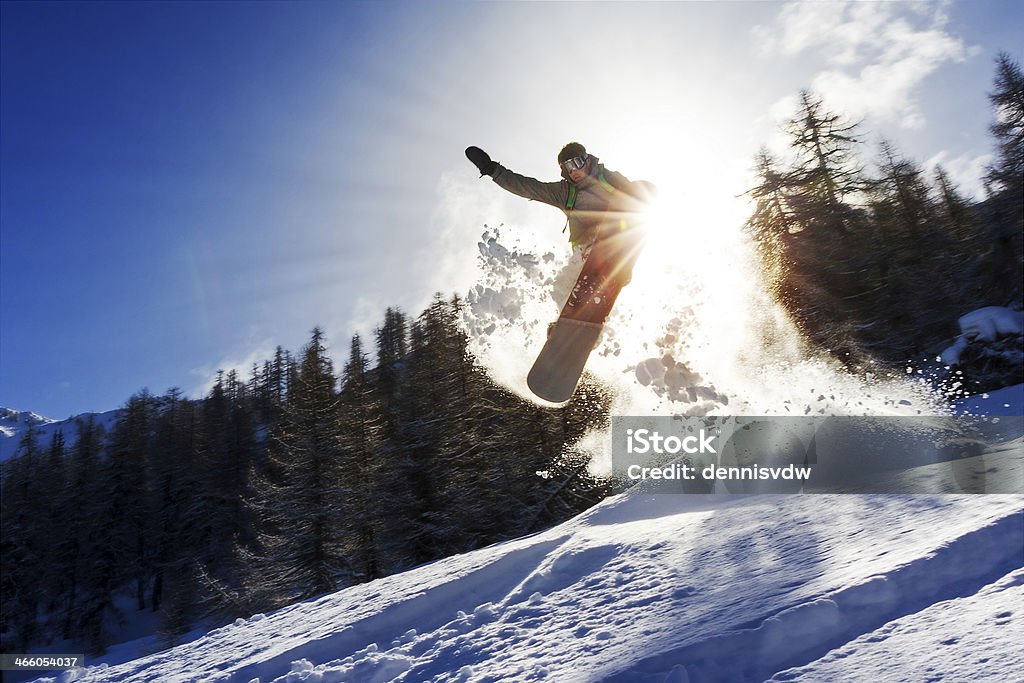 Snowboard sun power Powerful image of a snowboarder jumping over a kicker in the backcountry powder Snowboarding Stock Photo