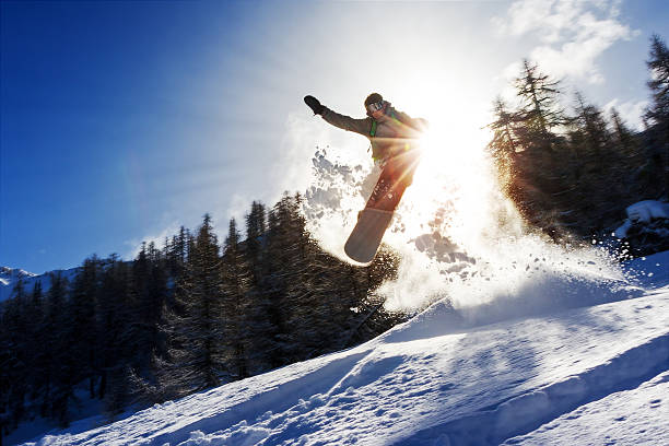 Snowboard sun power Powerful image of a snowboarder jumping over a kicker in the backcountry powder snowboarding stock pictures, royalty-free photos & images