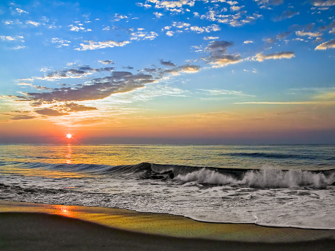 The sun rises over vreaking waves on the beach at Fenwidk Island, Delaware.