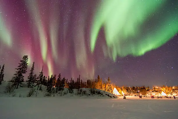 Photo of Aurora Borealis over tepees in Yellowknife