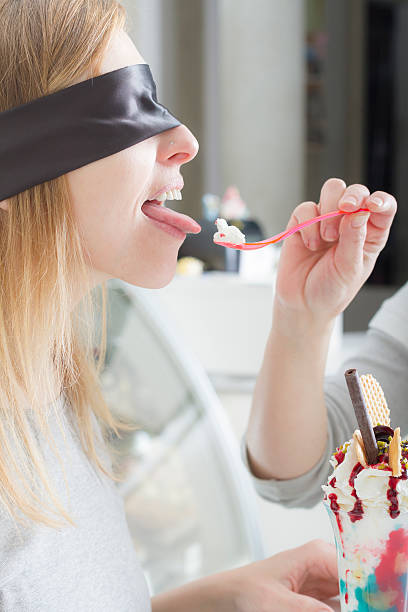 blindfolded mujer joven degustación de helado - spoon tasting women sex symbol fotografías e imágenes de stock