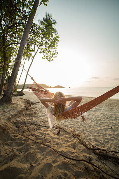 donna sulla spiaggia tropicale sdraiato su un'amaca-al-tramonto - hammock beach vacations tropical climate foto e immagini stock