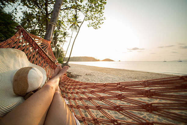 Woman resting on hammock on tropical beach Young woman on a tropical beach in Thailand lying down on a hammock relaxing. Sunset time on the Island. Shot with 5D Mark III, point of view from the woman's perspective. hammock stock pictures, royalty-free photos & images