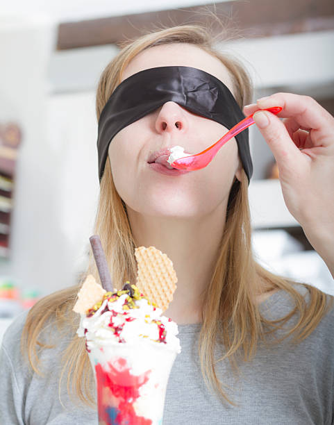 blindfolded mujer joven degustación de helado - spoon tasting women sex symbol fotografías e imágenes de stock