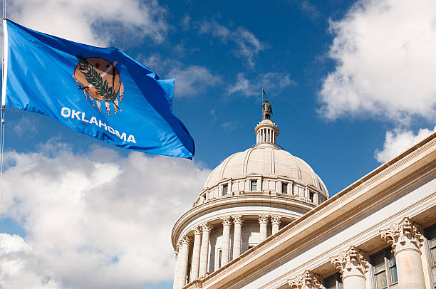 Oklahoma State Capitol Building and Flag State Capitol Building in Oklahoma City with US state flag outside on a partly cloudy day oklahoma stock pictures, royalty-free photos & images