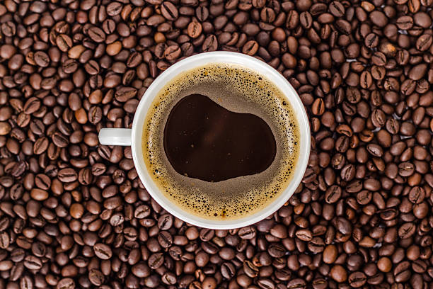 white cup of coffee on a heap of coffee beans. white cup of coffee on a heap of roasted coffee beans. Above from view. coffee liqueur stock pictures, royalty-free photos & images