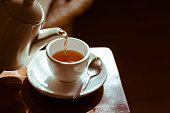 istock Tea cup on saucer, with tea being poured, 466073662