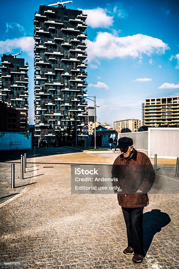 Uomo anziano cammina sotto il famoso palazzo dette Bosco, Milano - Foto stock royalty-free di 80-89 anni