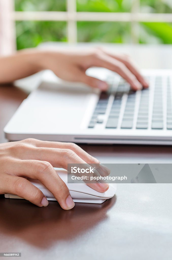 Hands working on a laptop with wireless mouse Woman using a mouse working on the computer 2015 Stock Photo