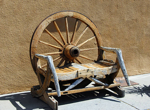 Bench western made Western design seat is a conglomeration of wagon wheel, old timber, boards and limbs.  Bench graces the plaza in "Old Town", Albuquerque, New Mexico with its nostalgic feel. wagon wheel bench stock pictures, royalty-free photos & images