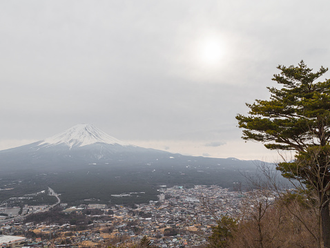 Japanese winter landscape with a huge volcano, Mount Fuji and the sun in the clouds above it