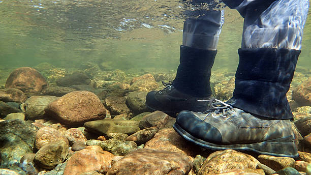 Underwater view of fly fisherman wading in river. stock photo