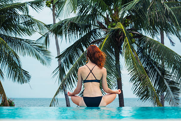 istock Young woman meditating by swimming pool 466110494