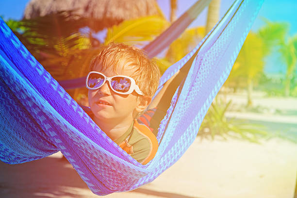 istock happy little boy relaxed in hammock on the beach 466111078