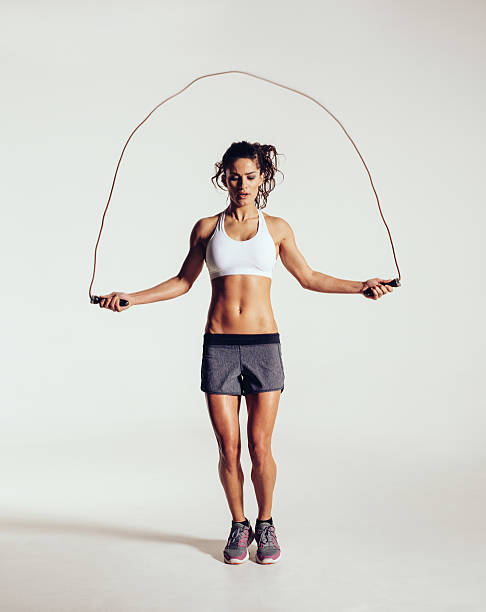 Fit young woman skipping rope Fit young woman skipping rope. Portrait of muscular young woman exercising with jumping rope on grey white background. skipping stock pictures, royalty-free photos & images