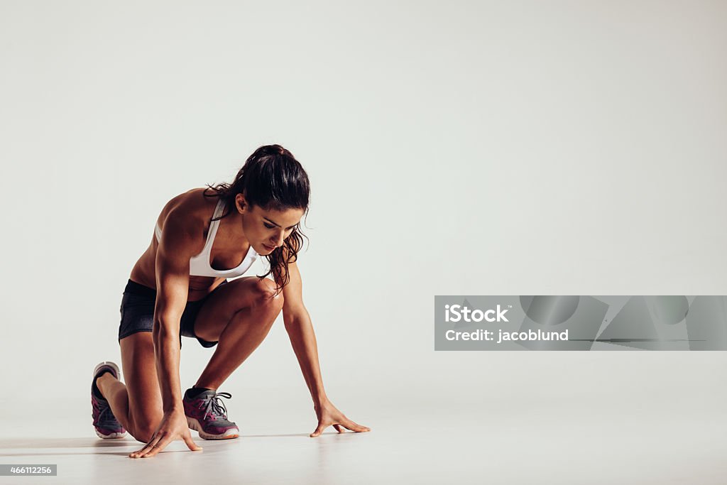 Healthy young woman preparing for a run Healthy young woman preparing for a run. Fit female athlete ready for a spring over grey background with copy space. Running Stock Photo