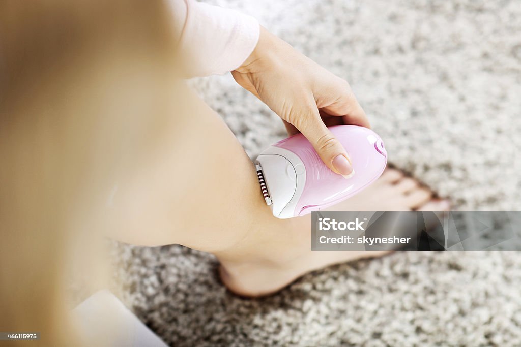 Woman epilating her leg. Unrecognizable woman epilating her leg. Epilator Stock Photo