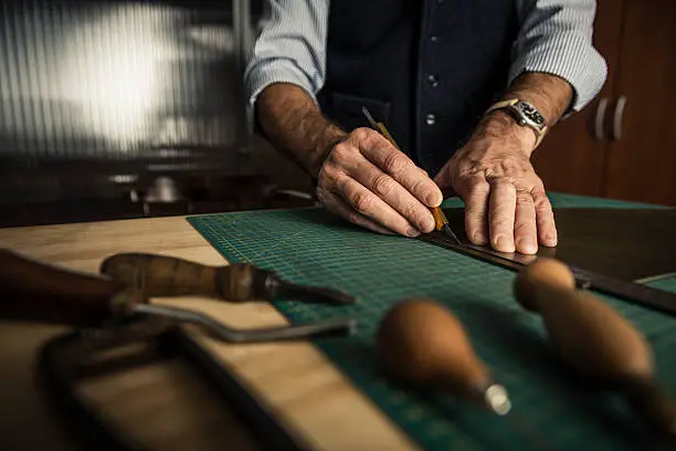 Close up shoot of an artisan working with leather in his laboratory.