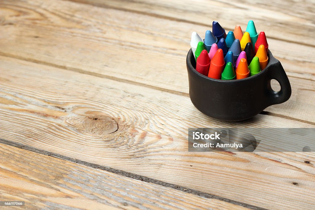 Black mug with oil pastel crayons Crayons in a mug on a wooden table. Selective focus, copy space background 2015 Stock Photo