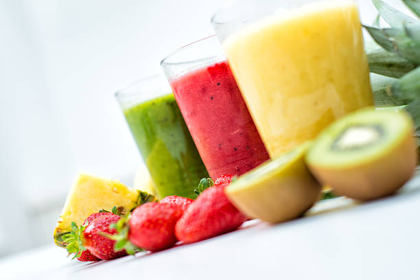 Fresh, healthy smoothies Three fresh, colorful smoothies with some fruit on white table. juice bar stock pictures, royalty-free photos & images