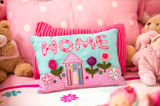 Close up view of a colourful cushion on a little girls bed with part of teddy bears can be seen.
