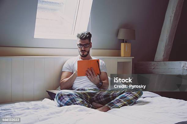 Man Reading A Book In Bed Stock Photo - Download Image Now - Attic, 2015, Adult
