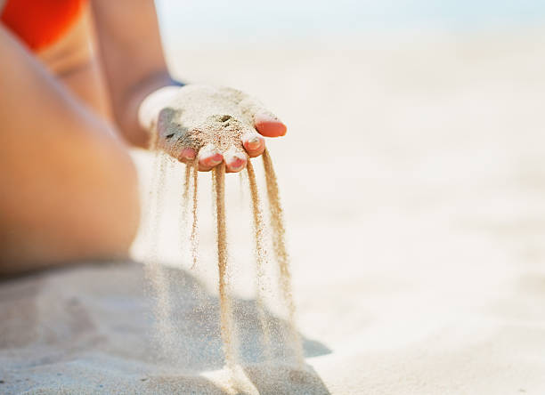 istock Young woman sitting on beach and playing with sand. Closeup 466134873