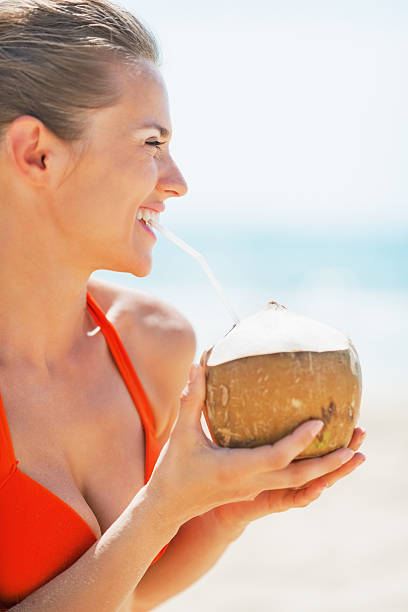 istock happy young woman drinking coconut milk on beach 466139573