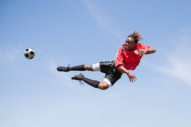 adulte de football joueur frappe de balle en l'air pendant le jeu - soccer player men flying kicking photos et images de collection