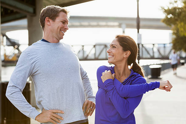 casal maduro estiver treinando juntos - couple stretching running jogging - fotografias e filmes do acervo