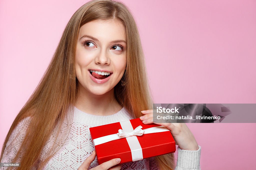 Joyful girl gift box pink background, Valentines Day, Women's Day Joyful girl in white sweater with a red gift box on the pink background, Valentines Day, holidays, happiness, International Women's Day 2015 Stock Photo