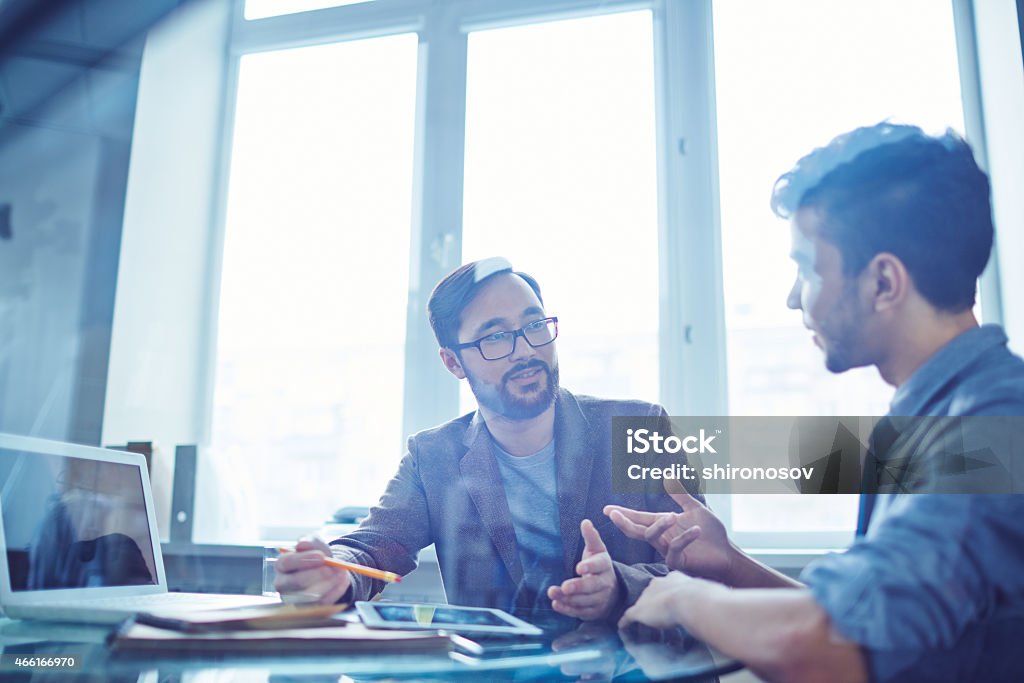 Exchanging ideas Male colleagues communicating during work 2015 Stock Photo