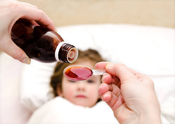 istock Mother pouring medication in a spoon in the foreground 466170497