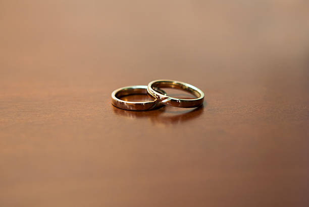 istock two gold wedding rings on a wooden table 466172039