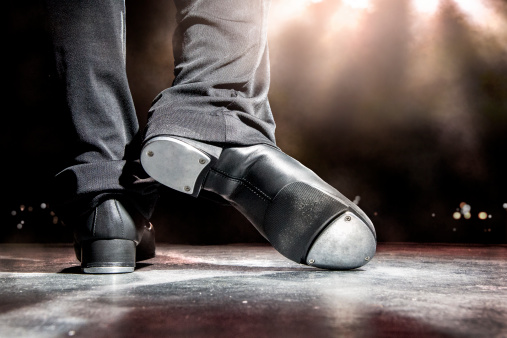 Male tap dancer, stands on stage with lighting and fog. Shallow dof. Visible noise and fog.