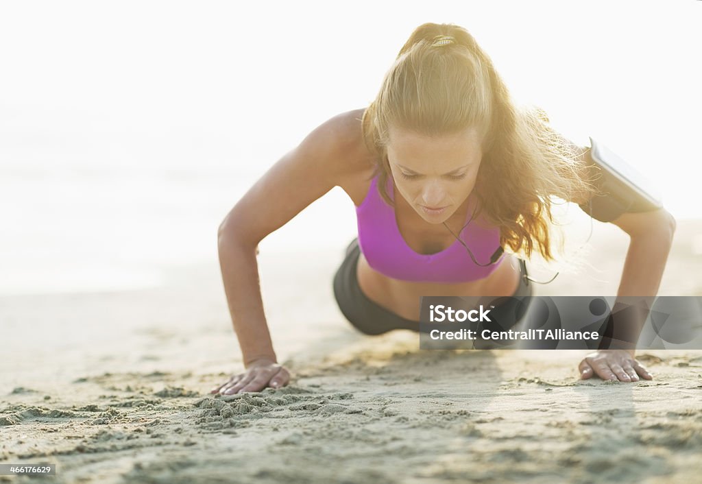 fitness young woman doing push ups on beach Fitness young woman doing push ups on beach Active Lifestyle Stock Photo