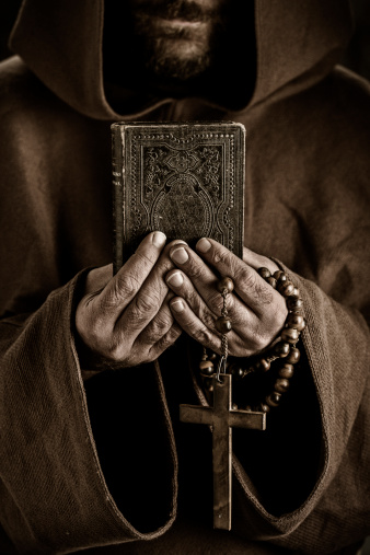 Monk holding small book and rosary in his hands