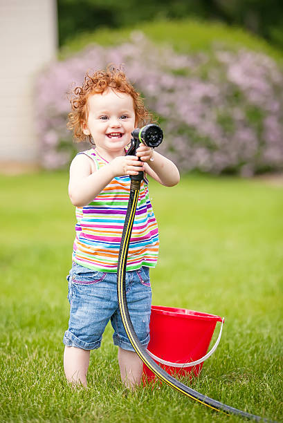 istock Girl Holding Garden Hose 466177507