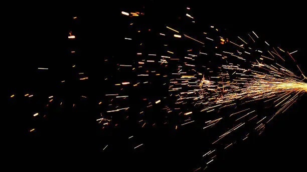 Glowing sparks coming from a grinder against a black background