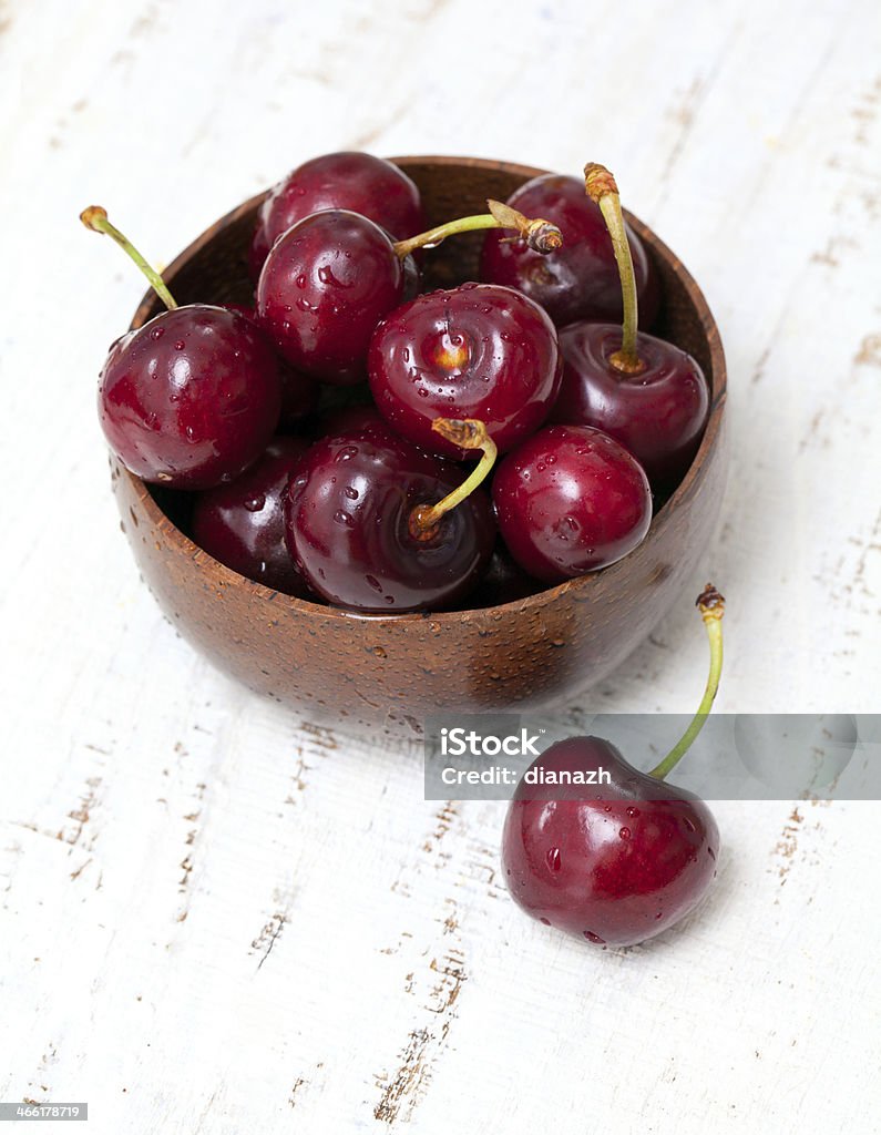 Cereja em uma tigela de madeira com superfície - Foto de stock de Alimentação Saudável royalty-free