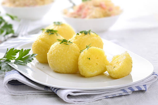 Potato dumplings Fresh potato dumplings on a white plate, sauerkraut with bacon strips in the background dumpling stock pictures, royalty-free photos & images